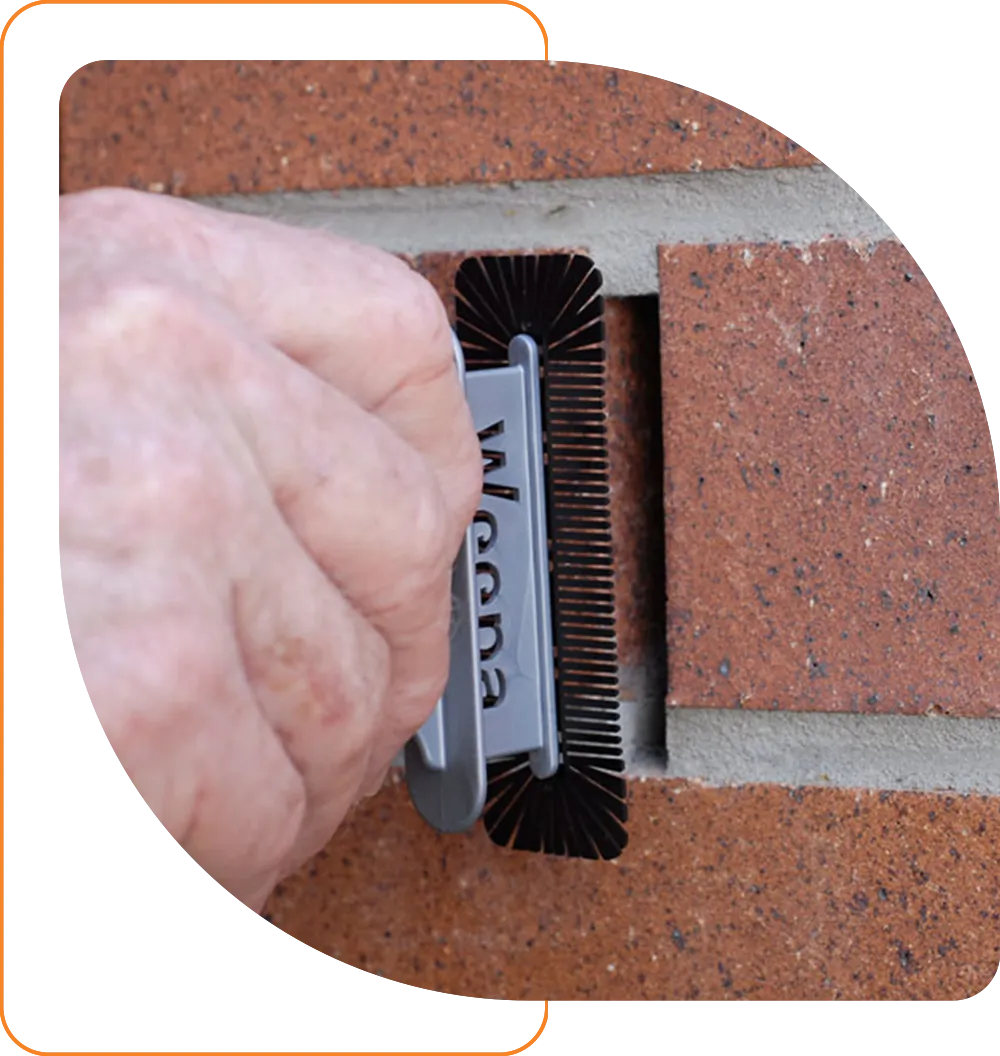 Hand inserting a Weepa Protector product into a weep hole