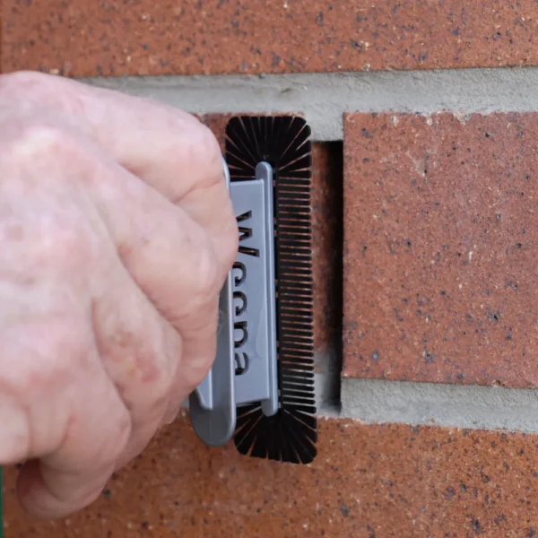 Hand inserting Weepa Termite Protect screen into brick wall